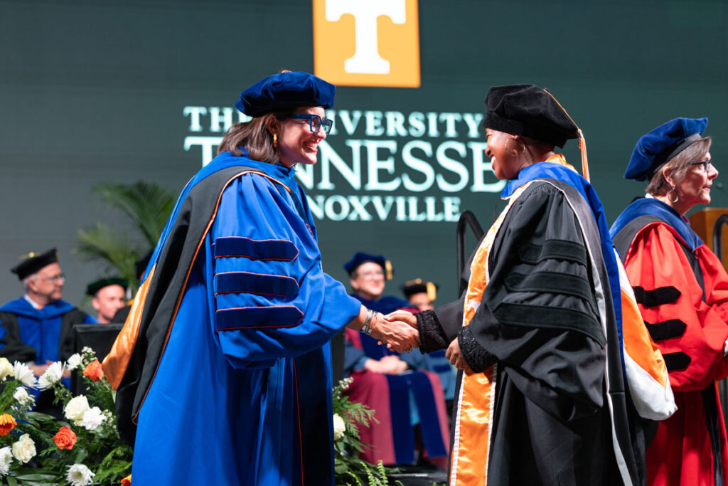 Vice Provost and Dean of the Graduate School Van Puymbroeck shaking hands with a newly hooded doctor.