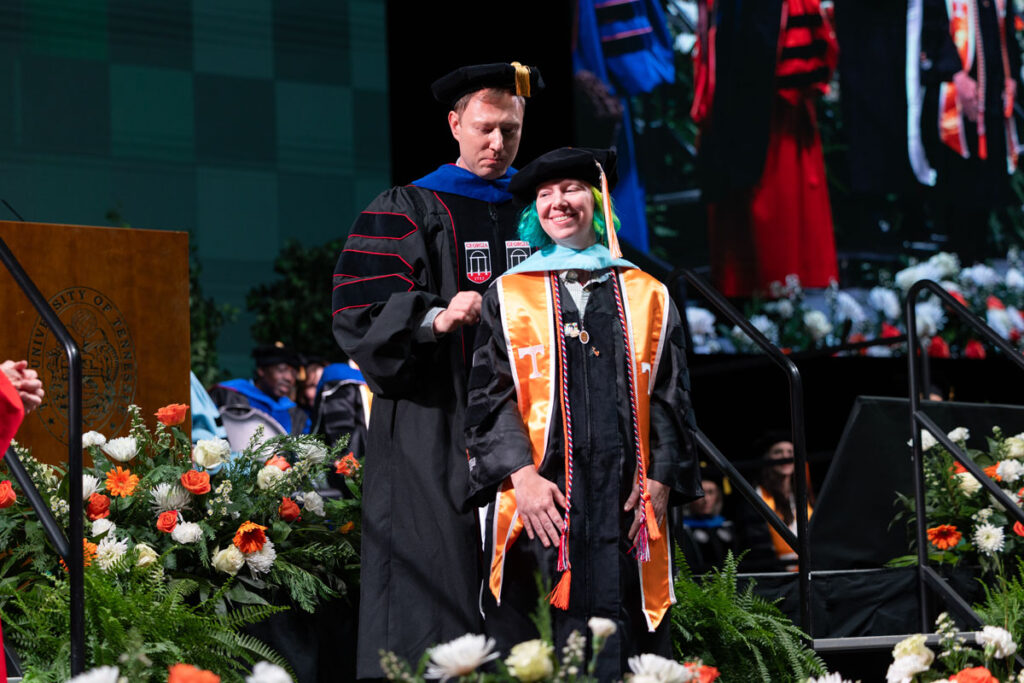Doctoral graduate being hooded by a member of the faculty.