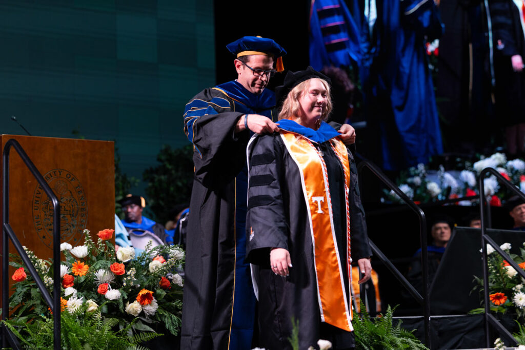 Doctoral graduate being hooded by a member of the faculty.