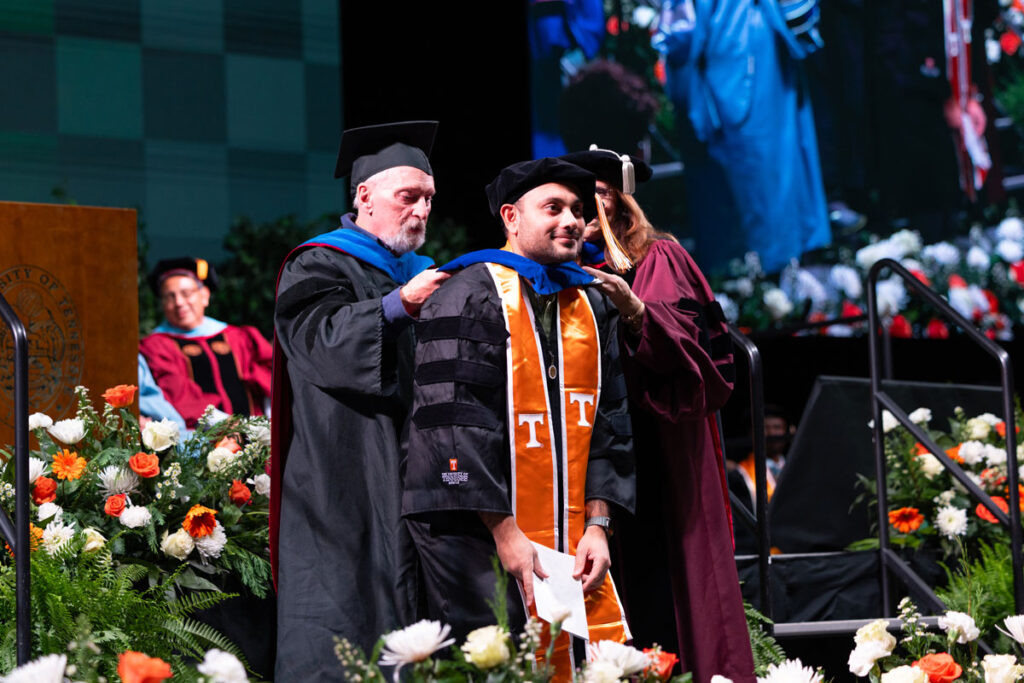 Doctoral graduate being hooded by a member of the faculty.