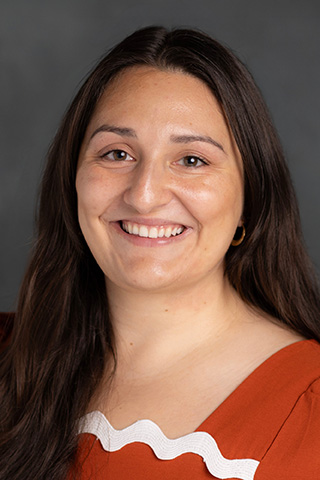 Headshot of woman with long hair smiling at the camera.