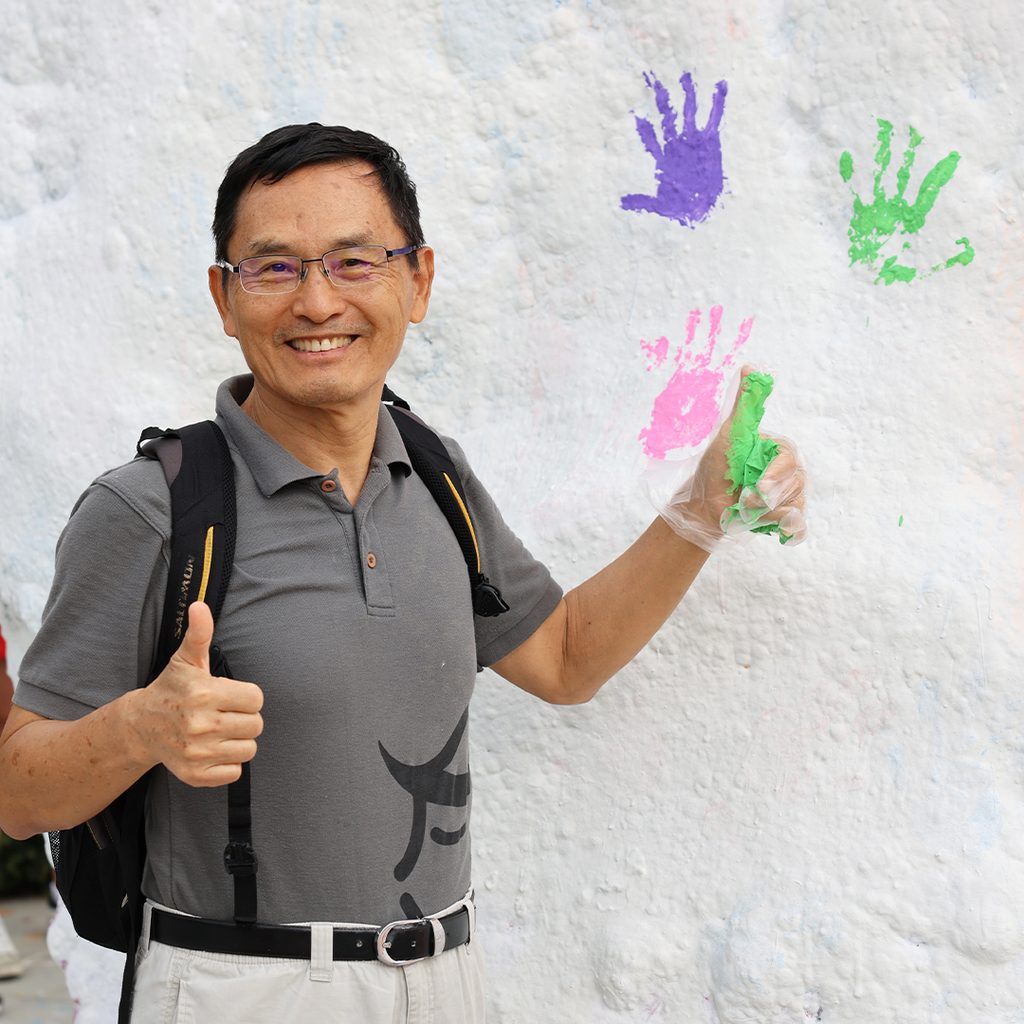 UTK researcher giving thumbs-up after painting the rock for National Postdoc Appreciation Week.